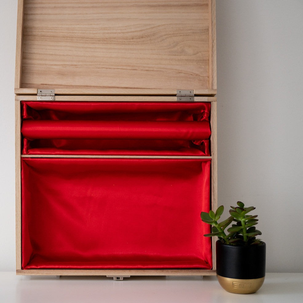 Open wooden box with red lining and bangle bar