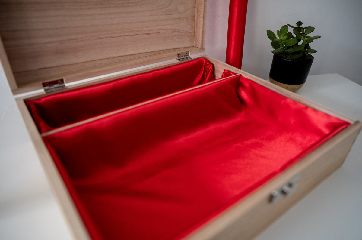 Open wooden box with red lining and bangle bar