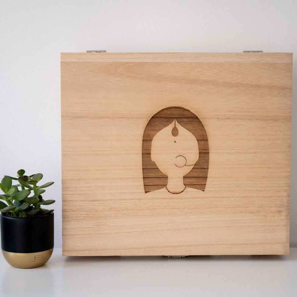 Wooden box with woman logo and small plant